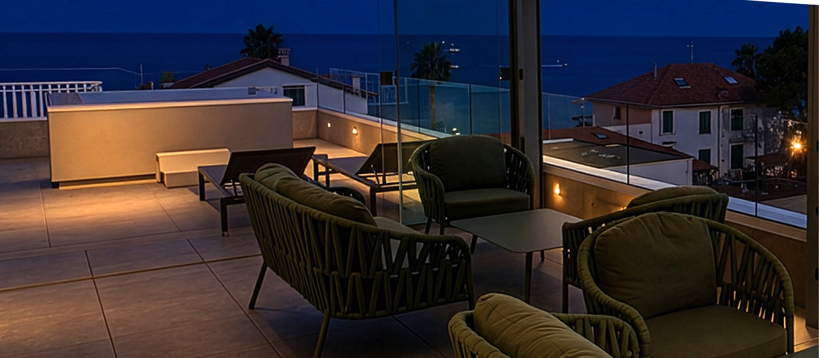 Rooftop lounge al tramonto con poltrone e vista sul mare