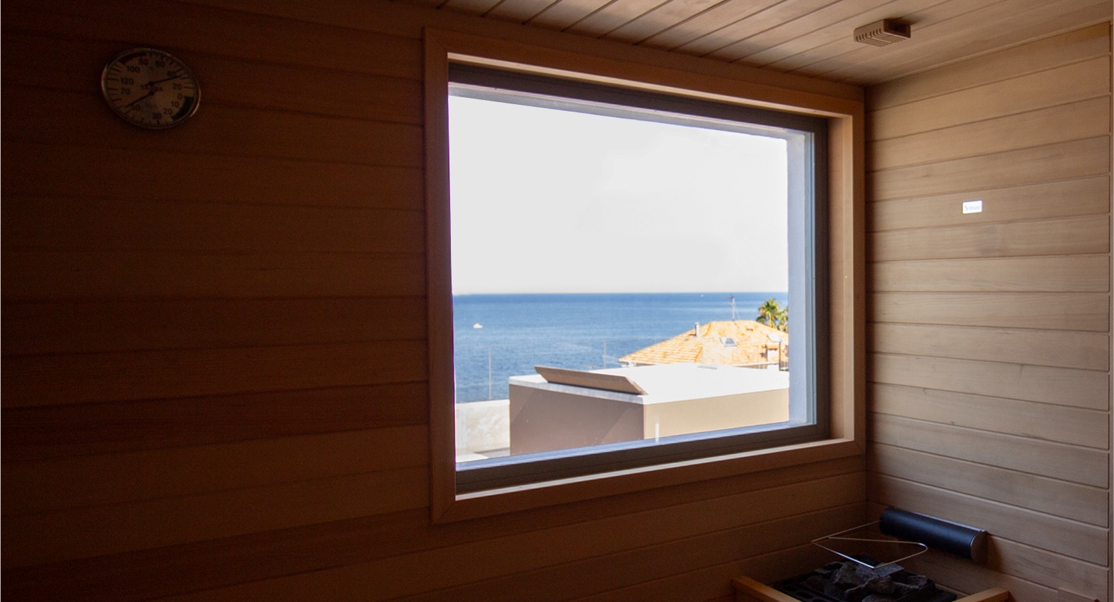 Sauna in legno con ampia finestra affacciata sul mare